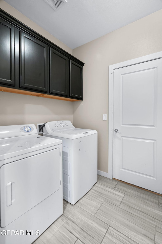 clothes washing area featuring cabinet space, independent washer and dryer, and baseboards