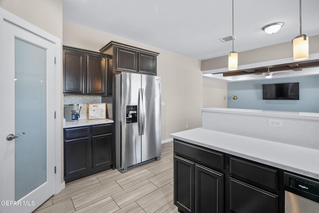kitchen featuring stainless steel appliances, light countertops, decorative light fixtures, decorative backsplash, and baseboards