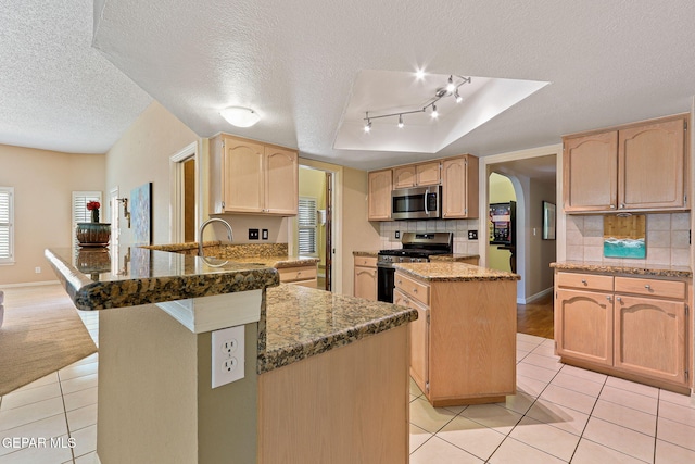 7008 Desert Canyon Dr, El Paso, TX 79912 - kitchen featuring stainless steel appliances, light tile patterned floors, a peninsula, a textured ceiling, and backsplash