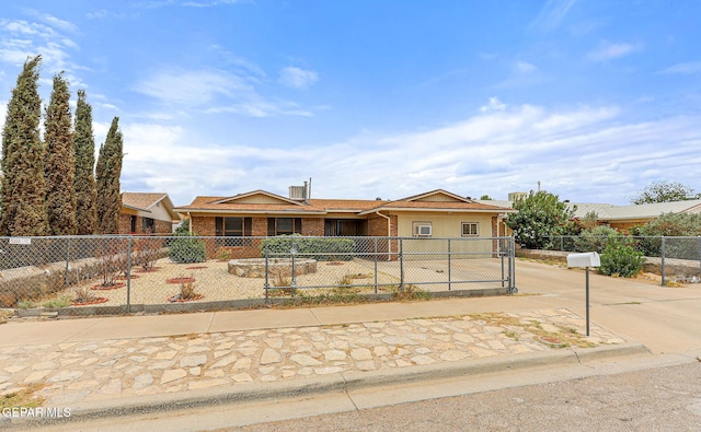 ranch-style home with a fenced front yard, driveway, and brick siding