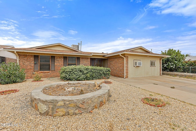 single story home featuring brick siding, fence, and a wall mounted air conditioner