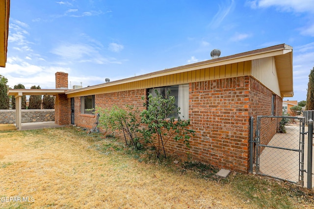 rear view of property featuring a gate, brick siding, and a chimney