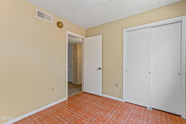 unfurnished bedroom with a textured ceiling, a closet, and baseboards