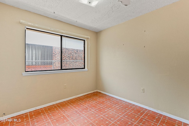 unfurnished room with baseboards and a textured ceiling