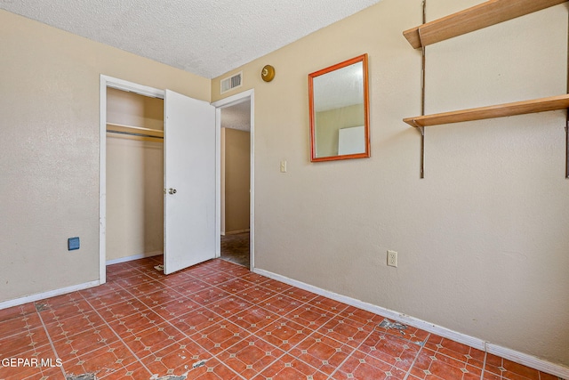 unfurnished bedroom with baseboards, a textured ceiling, a closet, and tile patterned floors