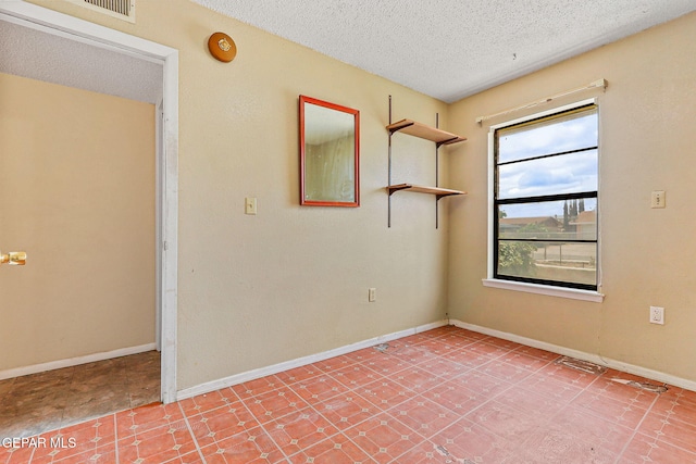 unfurnished room with a textured ceiling and baseboards