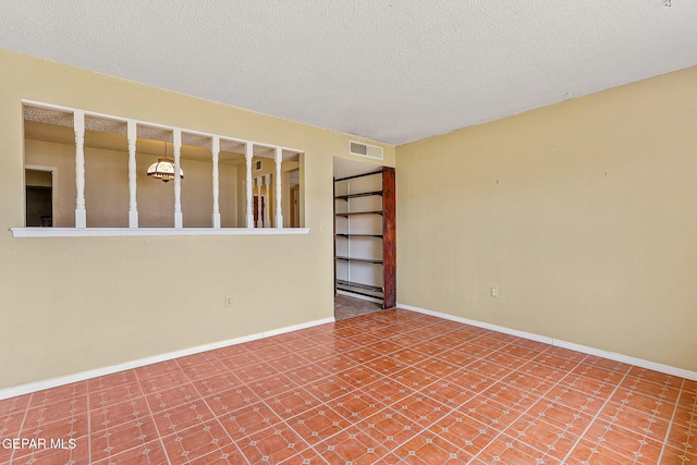 unfurnished room featuring a textured ceiling and baseboards