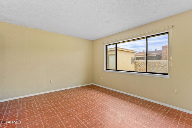 empty room featuring baseboards, a textured ceiling, and tile patterned floors