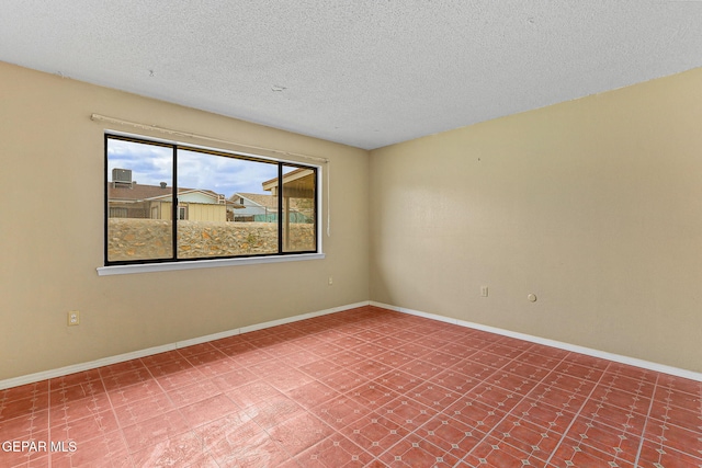 spare room with a textured ceiling, baseboards, and tile patterned floors