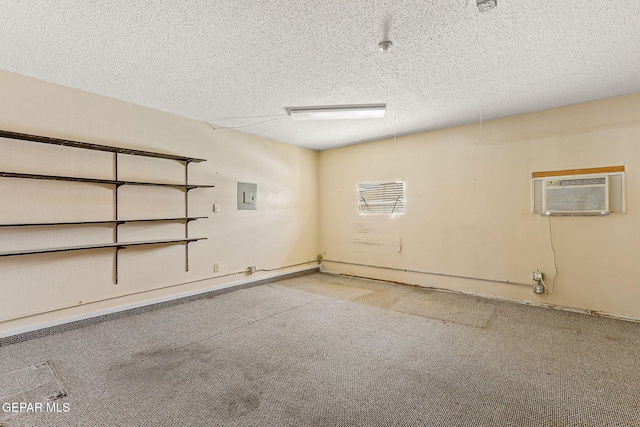 below grade area with a wall unit AC, a textured ceiling, electric panel, and baseboards