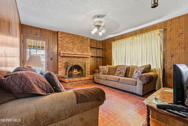 living area featuring wooden walls, a textured ceiling, ceiling fan, a fireplace, and built in features