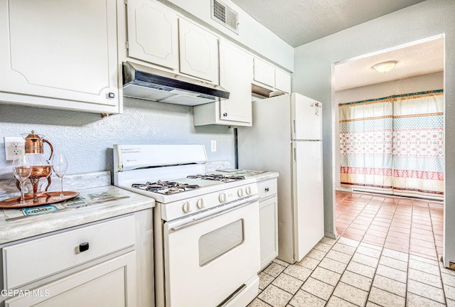 8520 Paddlefoot Ln, El Paso, TX 79907 - kitchen with white appliances, under cabinet range hood, white cabinets, light countertops, and brick patterned flooring