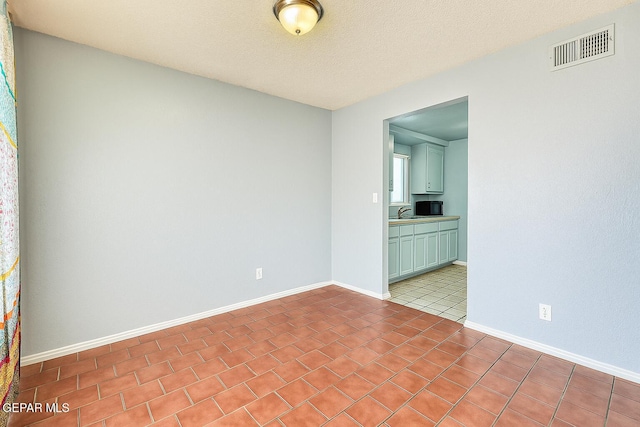 8520 Paddlefoot Ln, El Paso, TX 79907 - spare room featuring tile patterned flooring, a sink, a textured ceiling, and baseboards