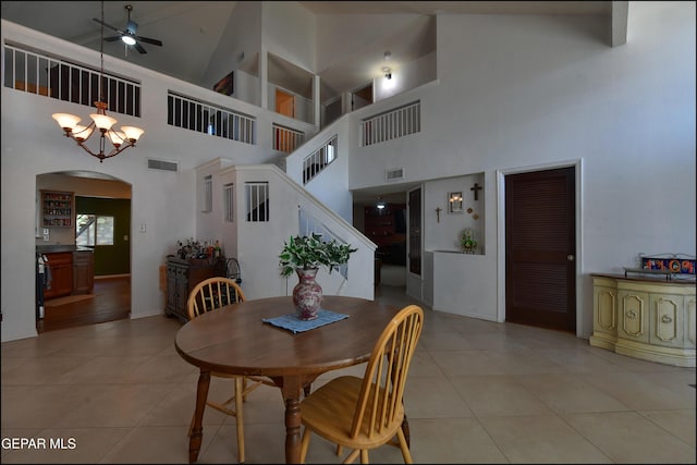 dining space with a ceiling fan, arched walkways, high vaulted ceiling, light tile patterned flooring, and baseboards