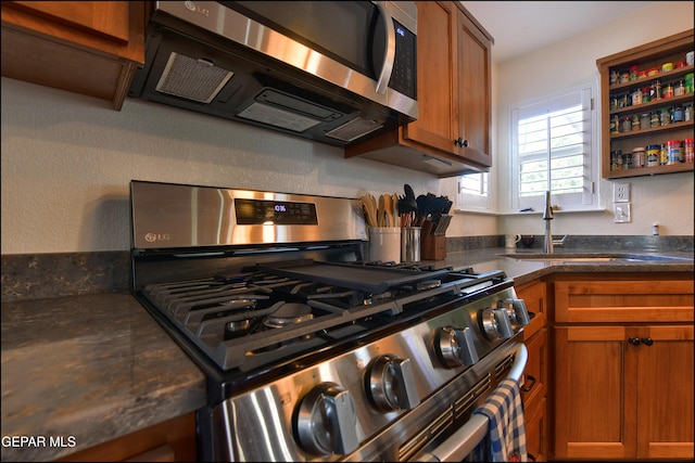 kitchen featuring appliances with stainless steel finishes, brown cabinets, and a sink