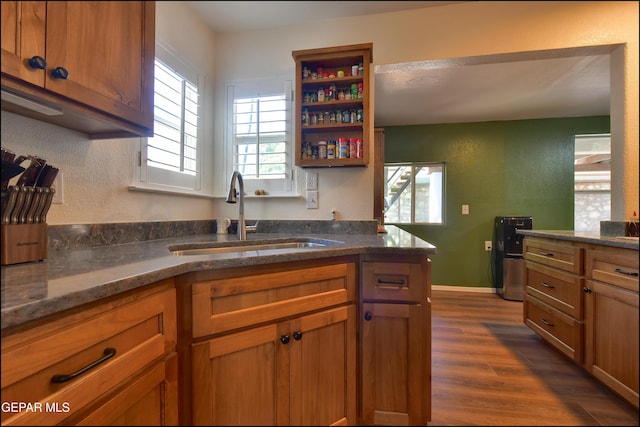 kitchen featuring a sink, dark wood-style floors, brown cabinetry, and dark stone countertops