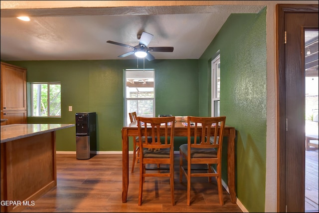 dining space featuring a textured wall, dark wood-type flooring, healthy amount of natural light, baseboards, and a ceiling fan