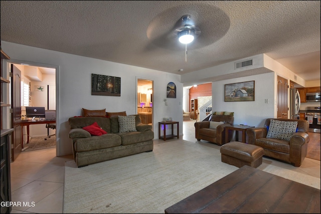living room featuring ceiling fan, light tile patterned floors, healthy amount of natural light, a textured ceiling, and an office area