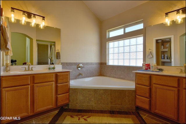 full bath with a bath, a shower stall, two vanities, tile patterned floors, and vaulted ceiling
