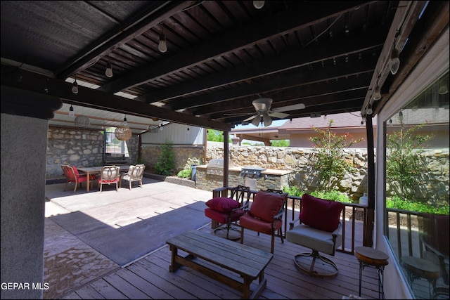 deck with outdoor dining area, an outdoor kitchen, ceiling fan, fence, and a patio