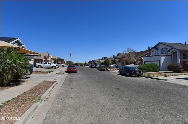 view of asphalt street with a residential view, sidewalks, and curbs