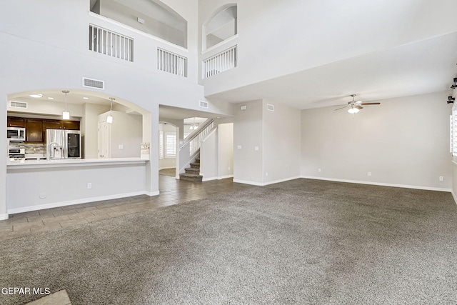 3136 Hawk Point Pl, El Paso, TX 79938 - unfurnished living room with ceiling fan, dark carpet, arched walkways, stairway, and baseboards