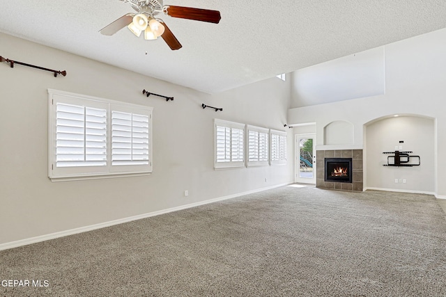 3136 Hawk Point Pl, El Paso, TX 79938 - unfurnished living room with a ceiling fan, carpet floors, a textured ceiling, a tiled fireplace, and baseboards