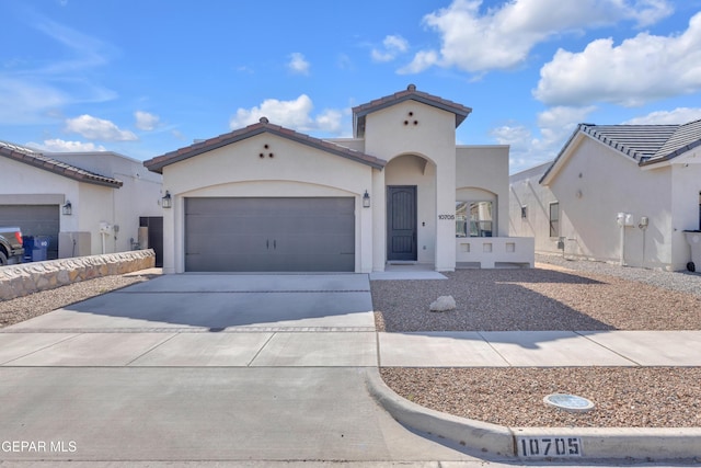 mediterranean / spanish house featuring driveway, an attached garage, and stucco siding
