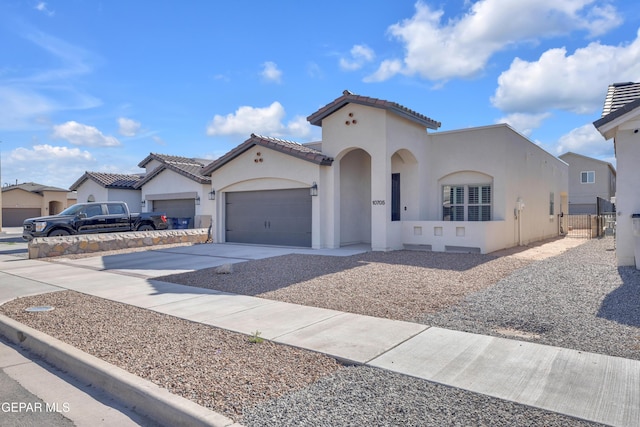 mediterranean / spanish-style house featuring driveway, stucco siding, an attached garage, a tiled roof, and fence