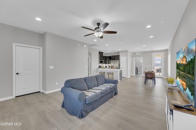 living room featuring ceiling fan, baseboards, and recessed lighting