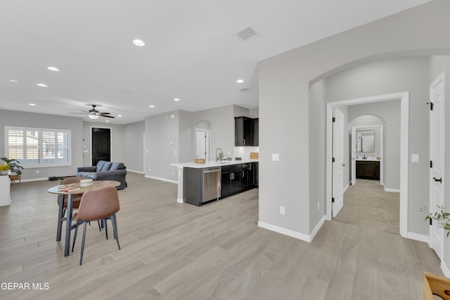kitchen featuring arched walkways, light countertops, open floor plan, ceiling fan, and baseboards