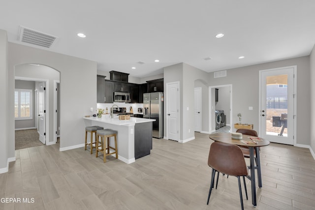 kitchen with appliances with stainless steel finishes, arched walkways, a kitchen breakfast bar, a peninsula, and recessed lighting