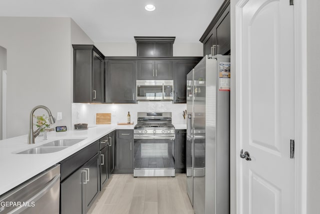 kitchen featuring stainless steel appliances, a sink, light countertops, backsplash, and recessed lighting