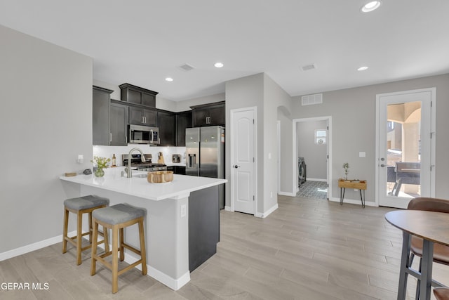 kitchen with stainless steel appliances, a peninsula, light countertops, baseboards, and recessed lighting