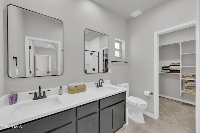 full bath with toilet, a walk in closet, and double vanity