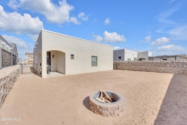 back of property with an outdoor fire pit, stucco siding, a fenced backyard, and a patio area