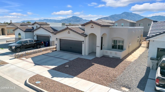 mediterranean / spanish house with a mountain view, stucco siding, concrete driveway, and an attached garage