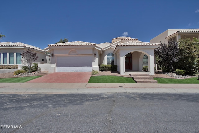 1483 Via Appia St, El Paso, TX 79912 - mediterranean / spanish house with stucco siding, an attached garage, driveway, and a tile roof