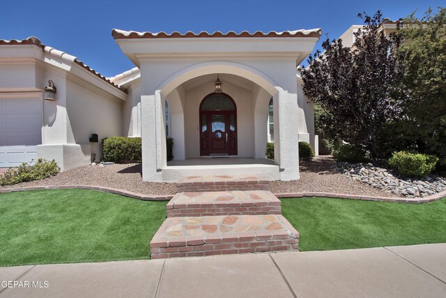 1483 Via Appia St, El Paso, TX 79912 - view of exterior entry featuring stucco siding, a tiled roof, an attached garage, and covered porch