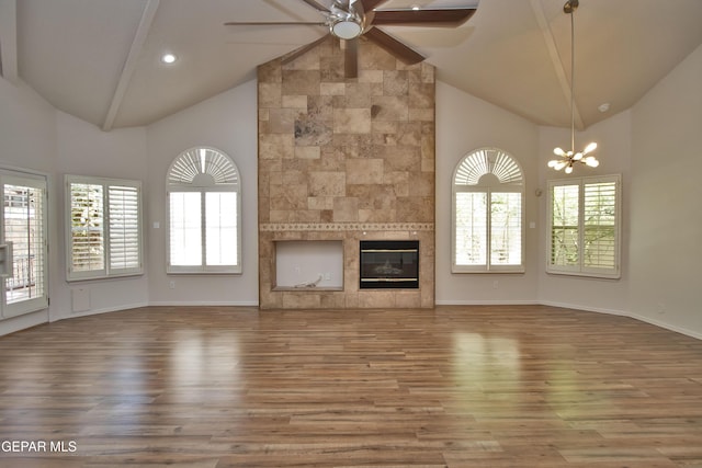 1483 Via Appia St, El Paso, TX 79912 - unfurnished living room with high vaulted ceiling, a ceiling fan, wood finished floors, a tiled fireplace, and a chandelier