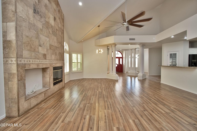 1483 Via Appia St, El Paso, TX 79912 - unfurnished living room featuring light wood-type flooring, ceiling fan, ornate columns, high vaulted ceiling, and a tile fireplace