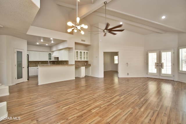 1483 Via Appia St, El Paso, TX 79912 - unfurnished living room featuring a chandelier, french doors, beam ceiling, light wood-type flooring, and high vaulted ceiling
