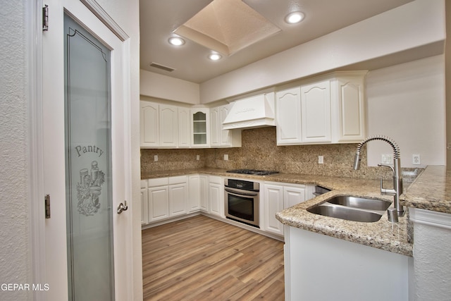 1483 Via Appia St, El Paso, TX 79912 - kitchen featuring stainless steel oven, a sink, premium range hood, light wood finished floors, and gas stovetop