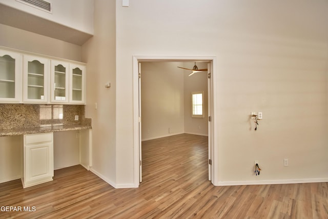 1483 Via Appia St, El Paso, TX 79912 - kitchen with light wood-style flooring, white cabinets, glass insert cabinets, and tasteful backsplash