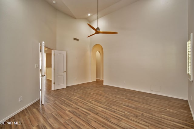 1483 Via Appia St, El Paso, TX 79912 - empty room featuring wood finished floors, baseboards, ceiling fan, arched walkways, and high vaulted ceiling