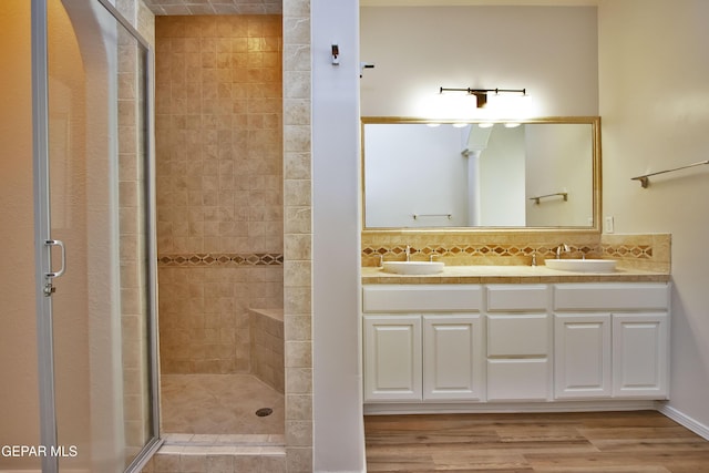 1483 Via Appia St, El Paso, TX 79912 - full bathroom featuring a shower stall, backsplash, double vanity, and wood finished floors