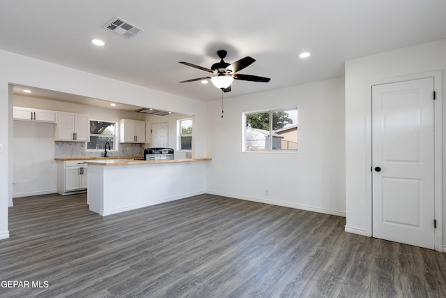 kitchen with dark wood-style flooring, white cabinets, range with gas stovetop, healthy amount of natural light, and recessed lighting