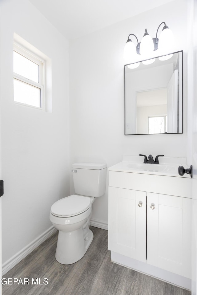 bathroom featuring toilet, wood finished floors, baseboards, and vanity
