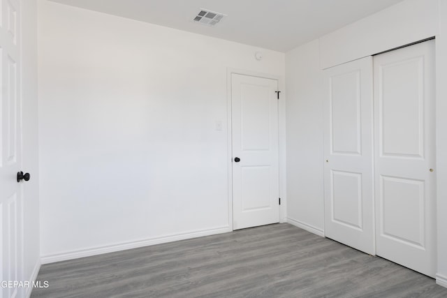 unfurnished bedroom with wood finished floors, a closet, and baseboards