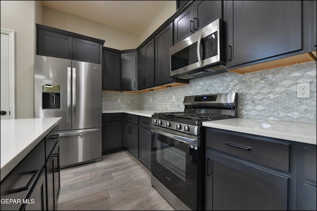 14844 Jack White Ave, El Paso, TX 79938 - kitchen with stainless steel appliances, light countertops, light wood-style flooring, and decorative backsplash